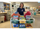 HUP Intensive Care Nursery clinical practice leader Whitney Zachritz, MSN, RN, CPNP-BC, stands behind a cart full of books and snacks.